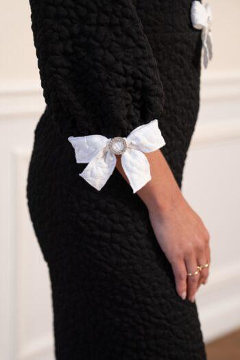 Détail des poignets ornés de nœuds blancs de la robe Havita